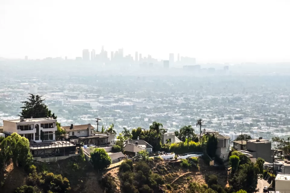 View of large mansions in Hollywood hills with downtown Los Angeles skyline in background.